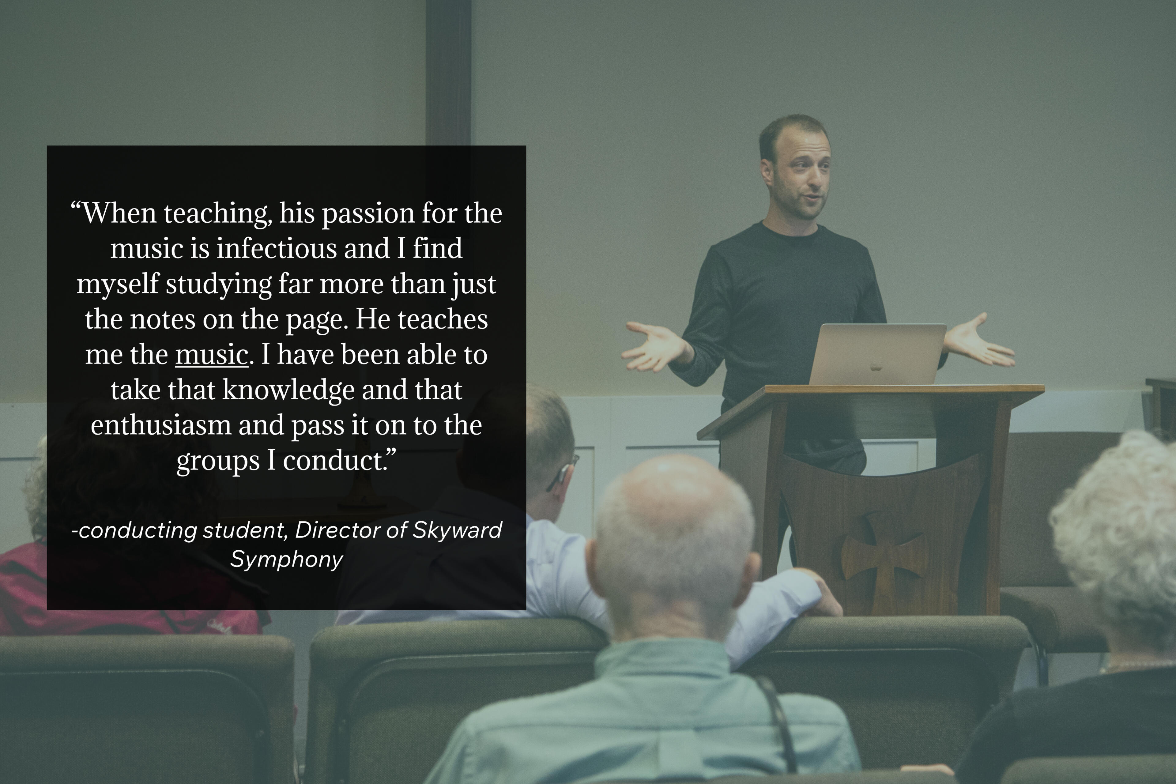 Photo by Wendy Redfern Dr. Matthew Mainella stands behind a wooden lectern with a laptop open in front of him. His hands are spread wide, his face is engaged - he appears to be talking about something he is excited about. The foreground has a quote from his conducting student.